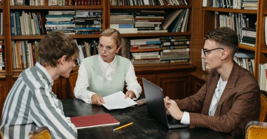 A group of adults engaged in conversation around a table in a library setting.